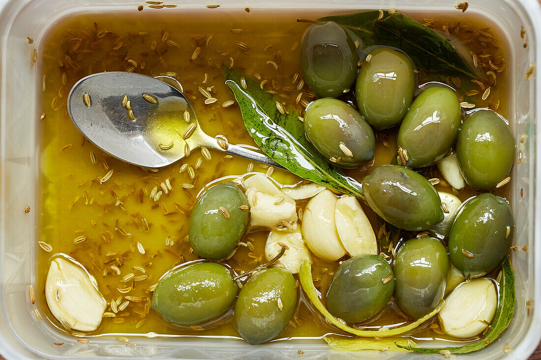 Grüne Oliven in Öl mit Knoblauch und Kreuzkümmel