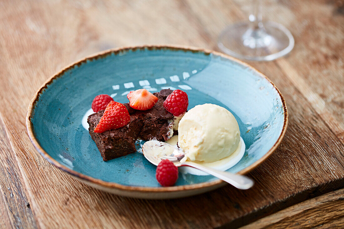 Chocolate brownie topped with strawberries and raspberries with a vanilla ice cream