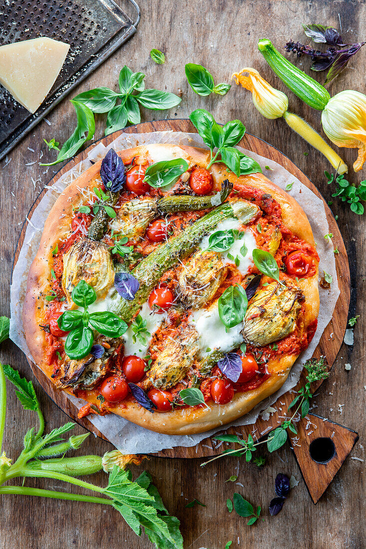 Pizza mit gefüllten Zucchiniblüten und Tomaten