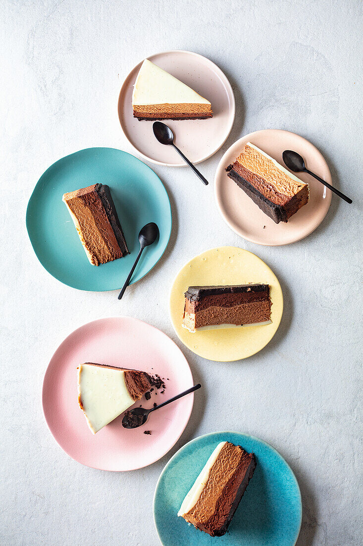 Dreifache Schoko-Mousse-Torte in Stücken auf Tellern