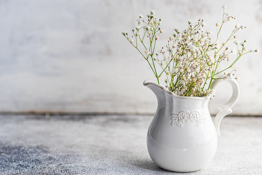 Weißes Schleierkraut (Gypsophila) in einem Keramikkrug auf Betonuntergrund