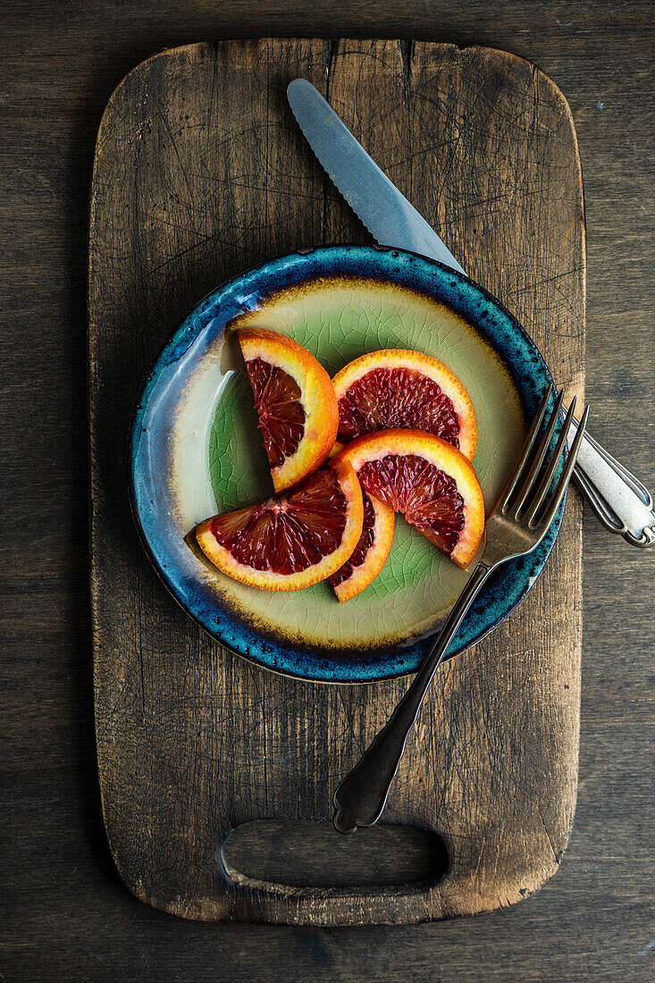 Red sicilian orange slice and vintage cutlery on rustic background