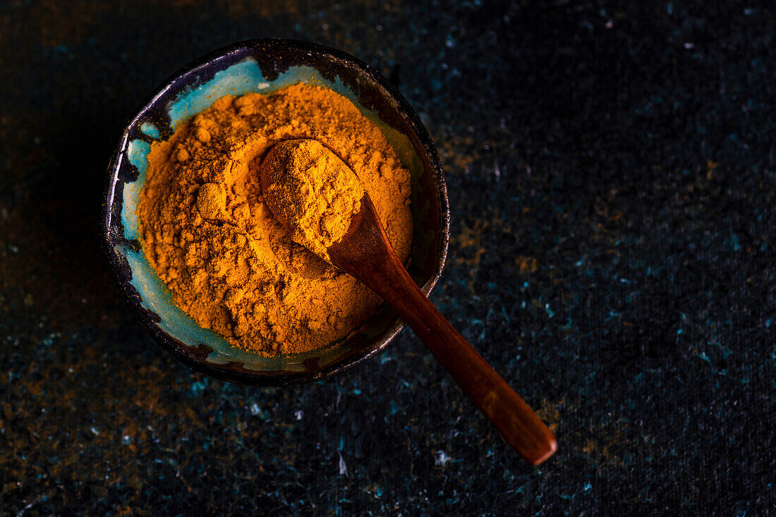Turmeric powder with a wooden spoon in a bowl