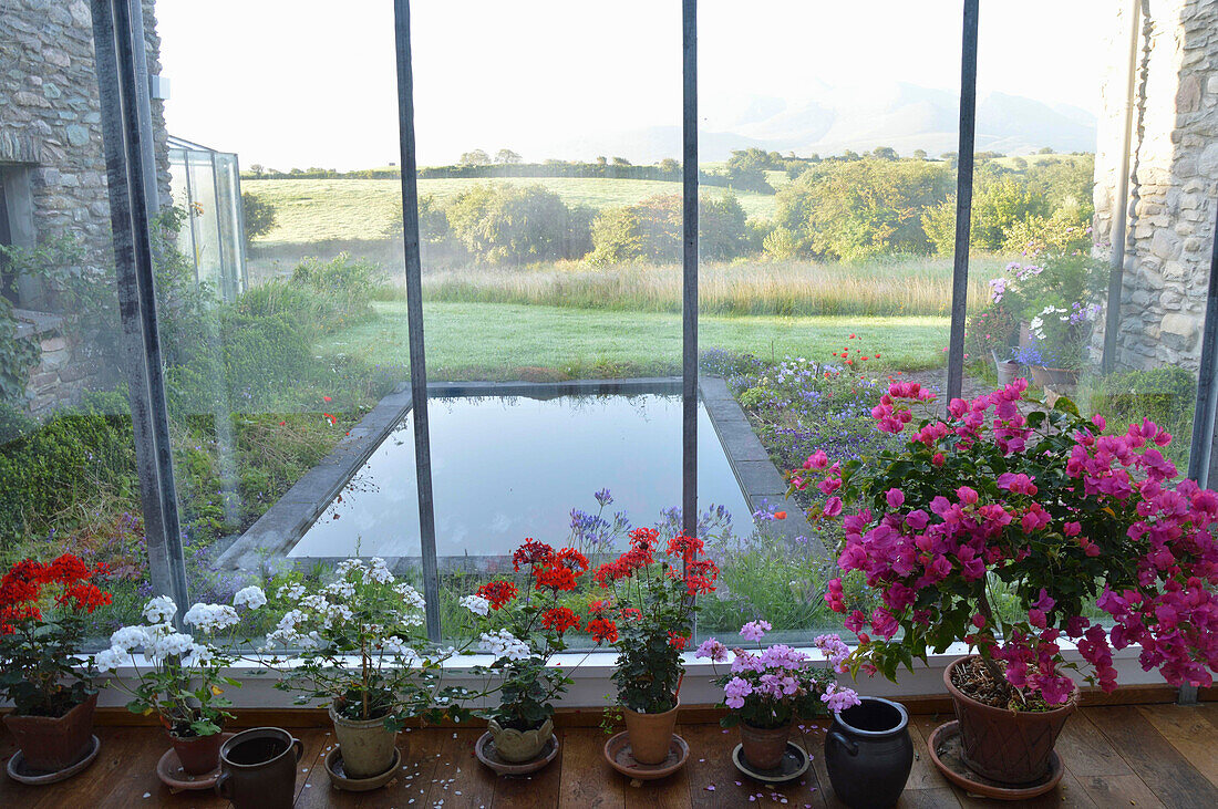 Wintergarten mit Blumen und Ausblick auf Teich und Landschaft