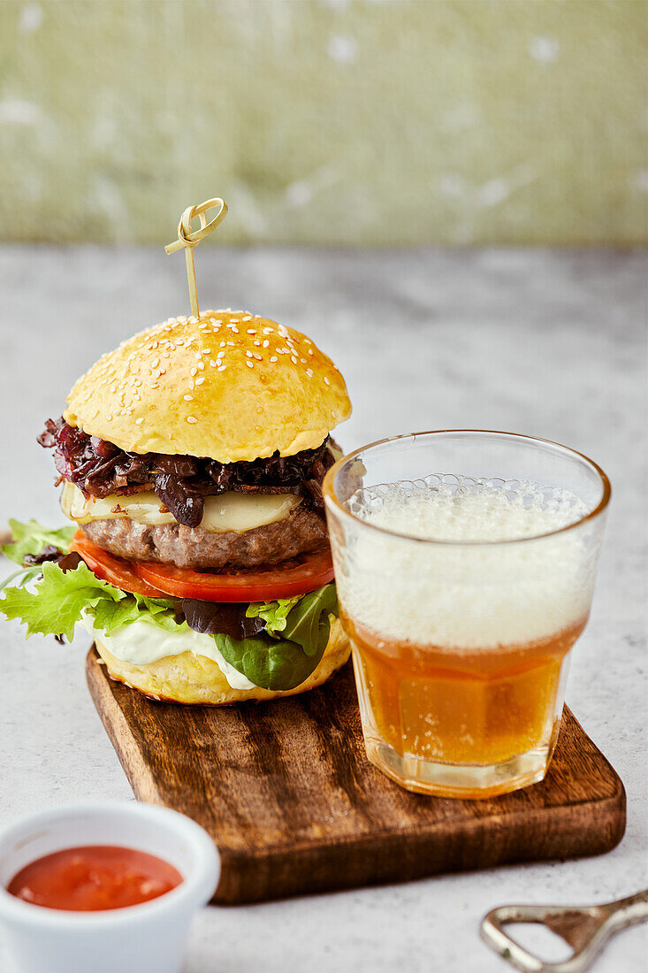 Cheeseburger with caramelized onions served with a glass of beer