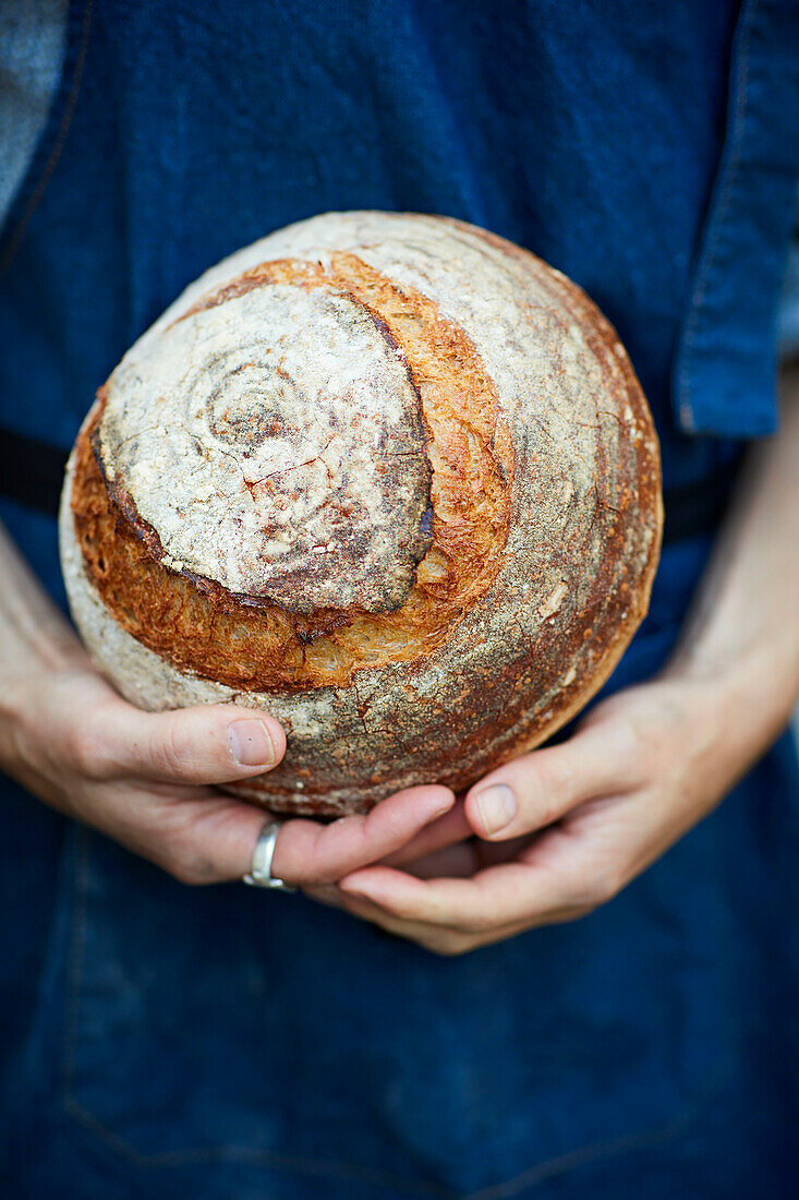 Sauerteigbrot in den Händen eines Bäckers