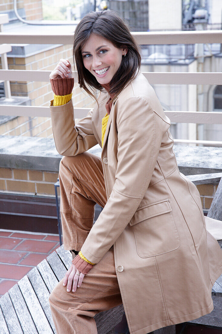 A brunette woman wearing an autumn outfit with a beige leather coat