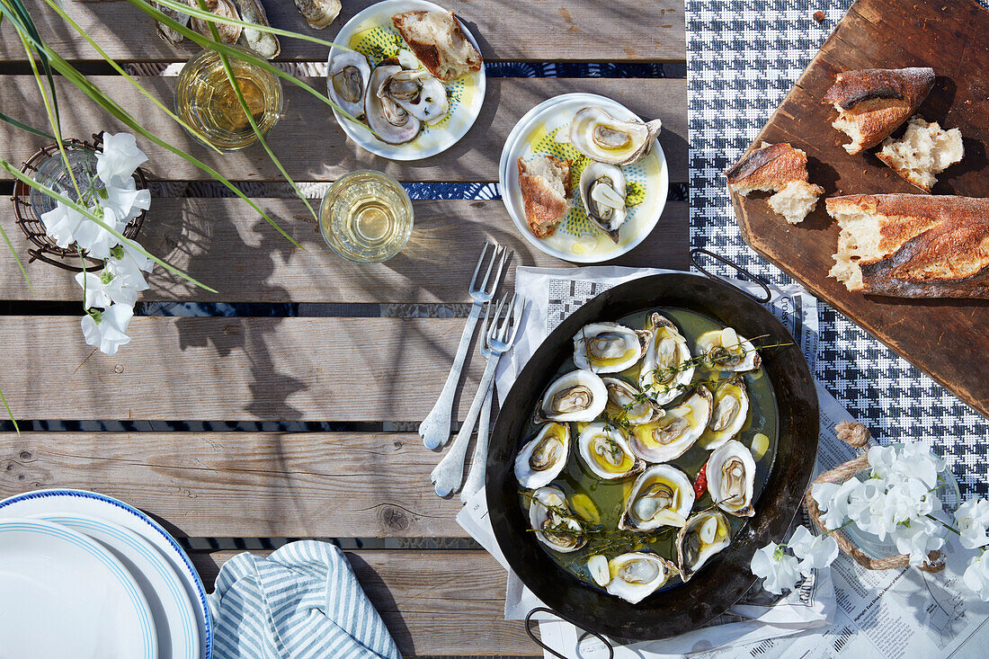 Austern serviert mit frischem Brot auf sommerlichem Tisch im Freien