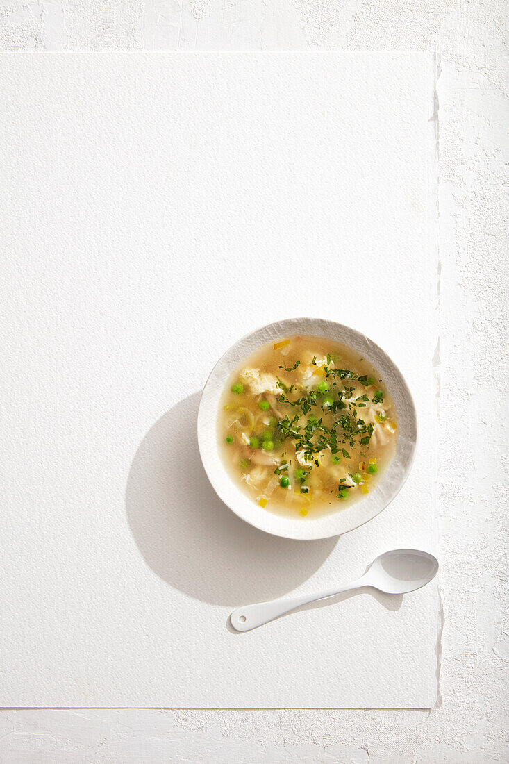 A bowl of homemade chicken soup on a white surface