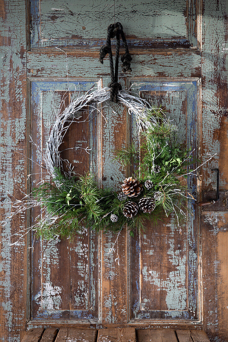 Weihnachtskranz an alter Holztür mit abblätternder Farbe