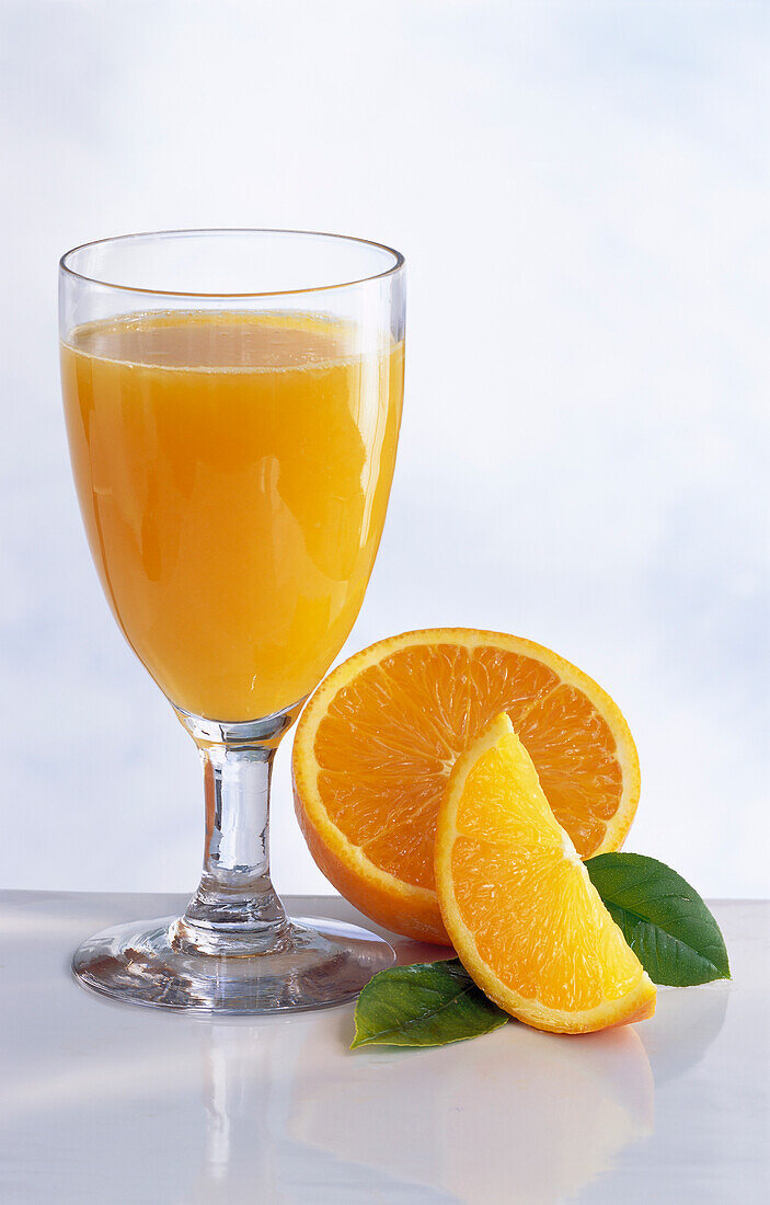 A glass of orange juice and oranges