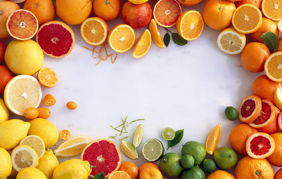 Various citrus fruits, whole and halved, grouped around the edge