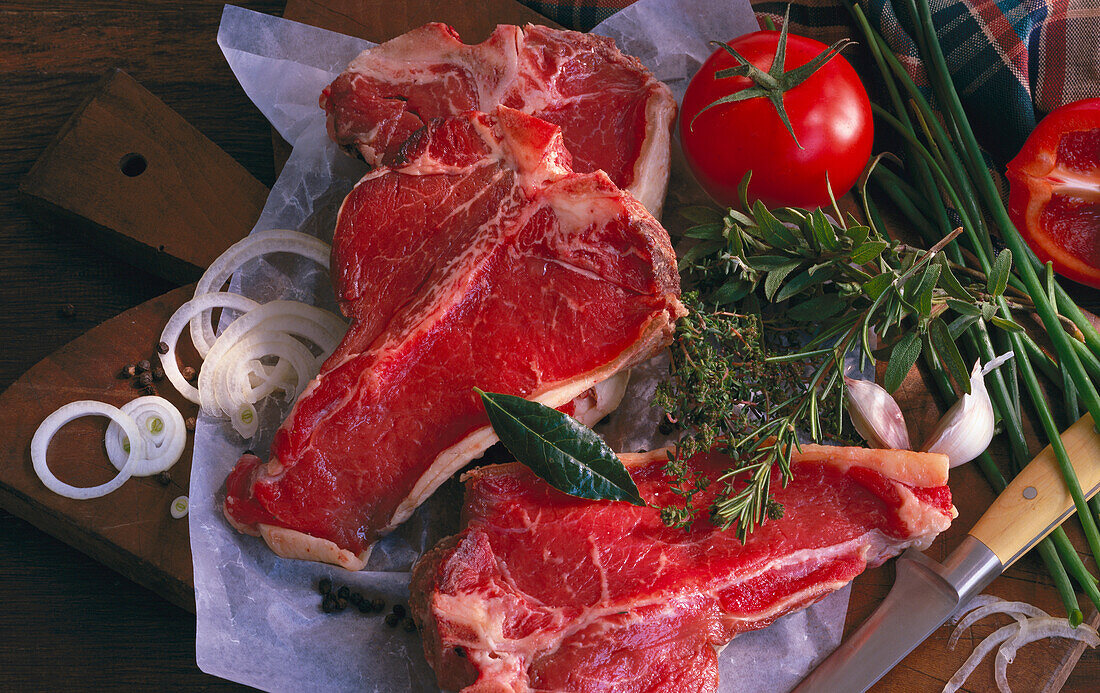 Stillleben mit Rindfleisch (T-Bone Steak), Kräutern, Pfeffer und Tomaten