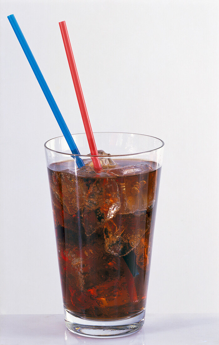 Ein Glas Cola mit Eiswürfeln und Strohhalmen