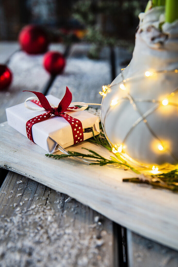 Wrapped gift with red ribbon and vase with fairy lights