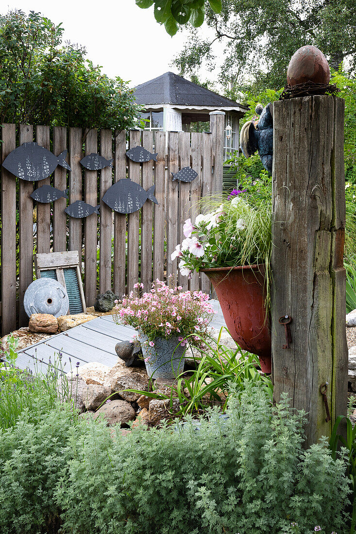 Fence decorated with plywood fish, in the foreground Roman wormwood (Artemisia pontica)