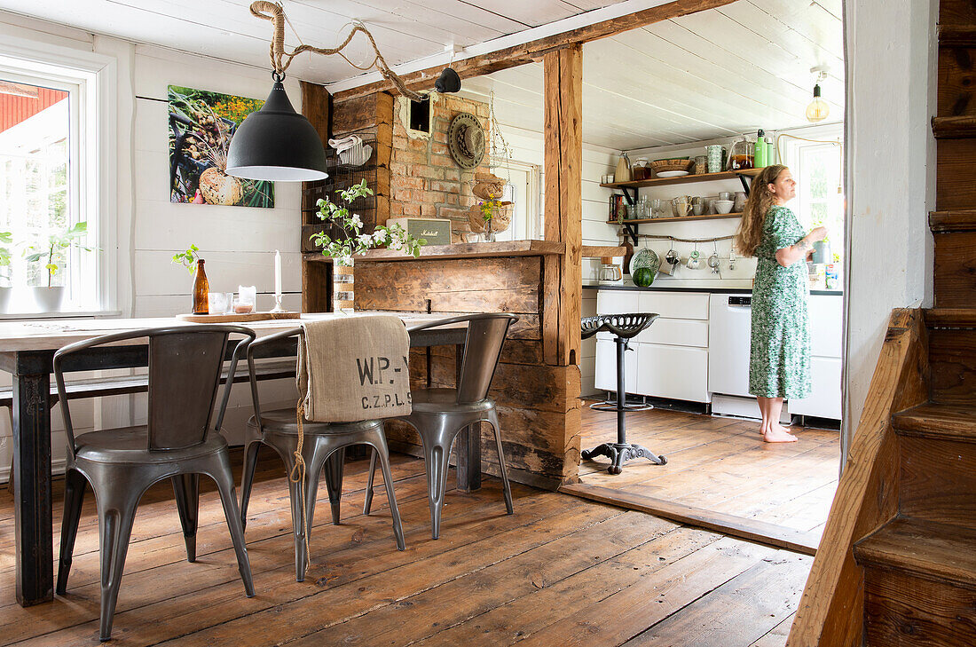 Rustic kitchen with dining table, metal chairs and woman in green dress