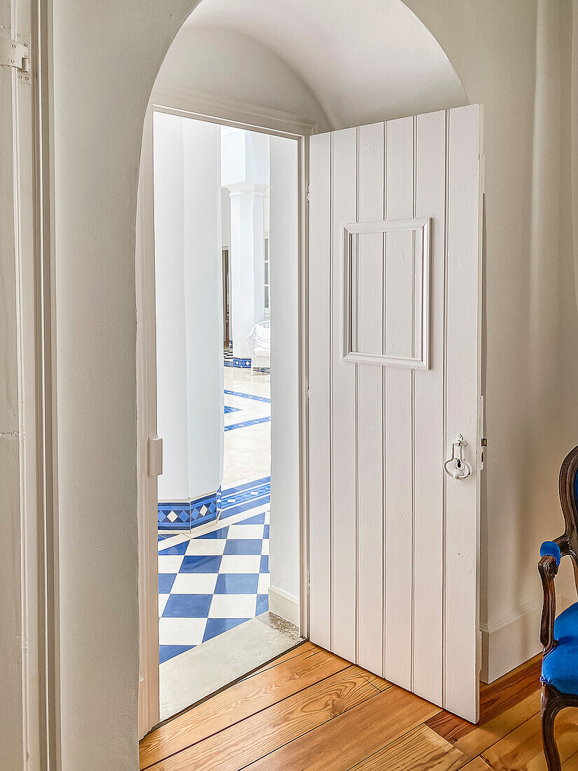 Passageway with white door to an inner courtyard with patterned tiles