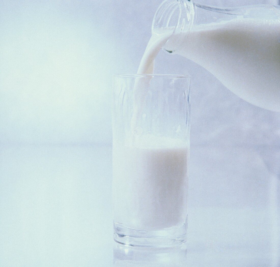 Milch wird aus einer Flasche ins Glas gegossen