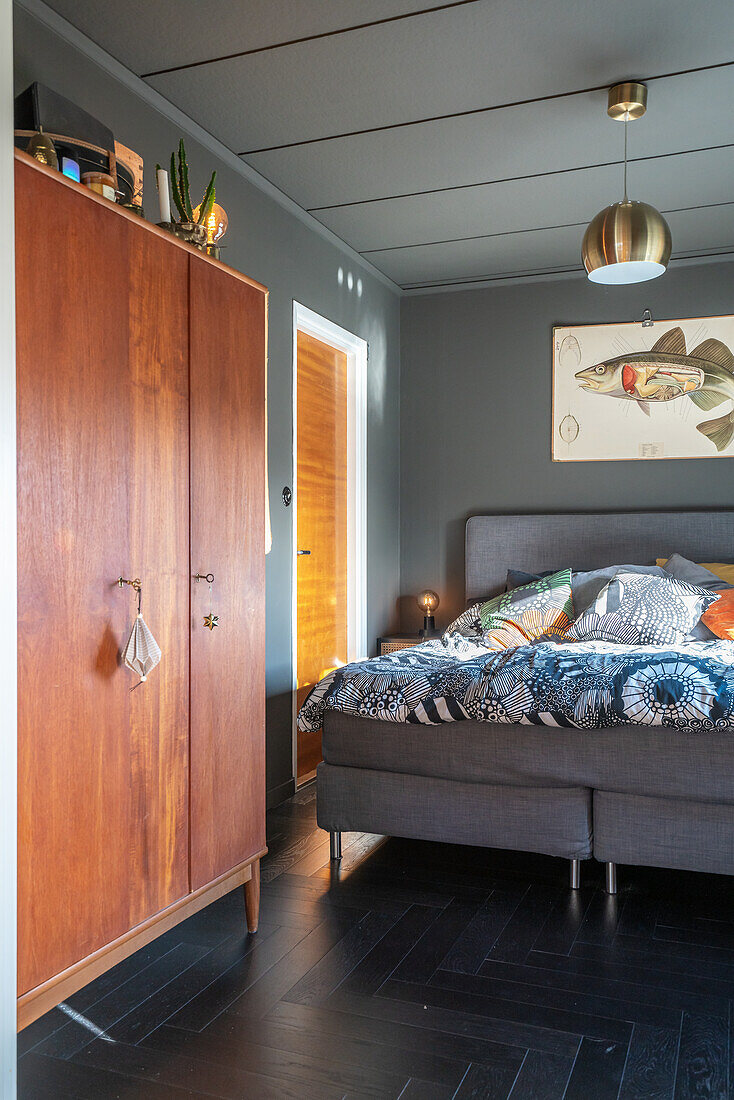 Teakholz-Schrank und Doppelbett im Schlafzimmer mit schwarzem Fischgrätparkett