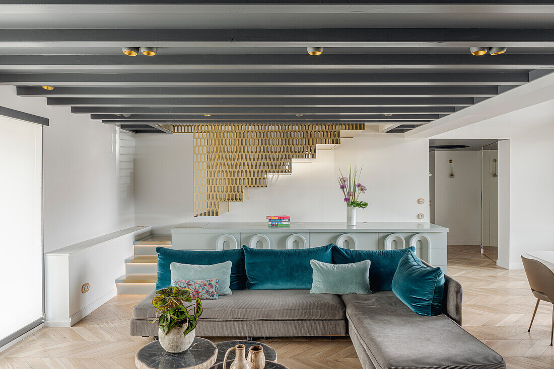 Grey corner sofa with blue cushions in front of a gray Art Deco sideboard in an open living room