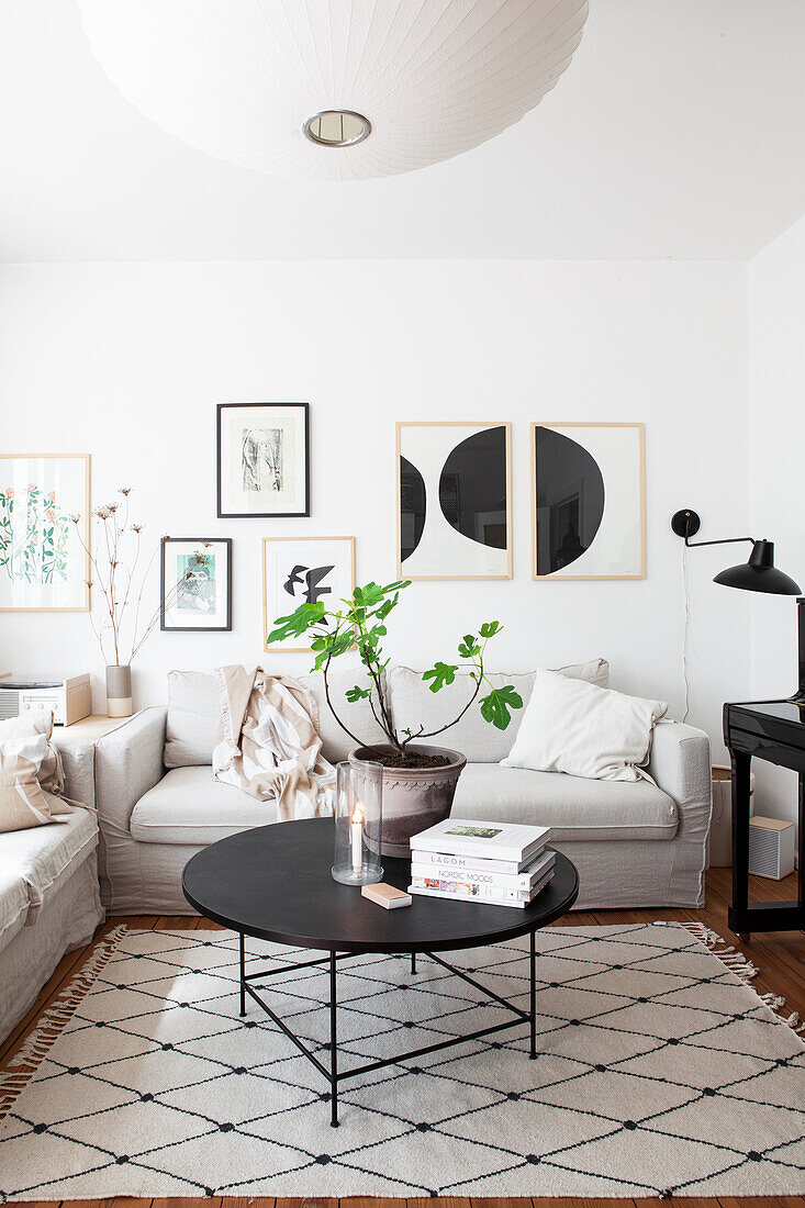 A black coffee table on a rug with a diamond pattern and a light upholstered sofa in a living room