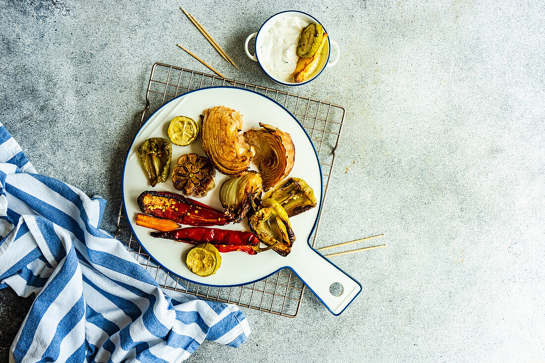 Healthy dinner with variety of BBQ vegetables served on ceramic dinnerware with sour cream sauce