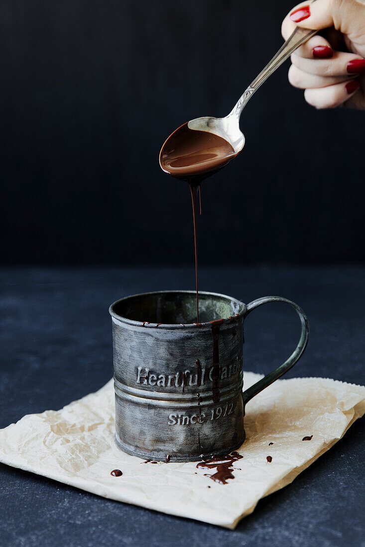 Liquid chocolate flowing from a spoon into a vintage cup