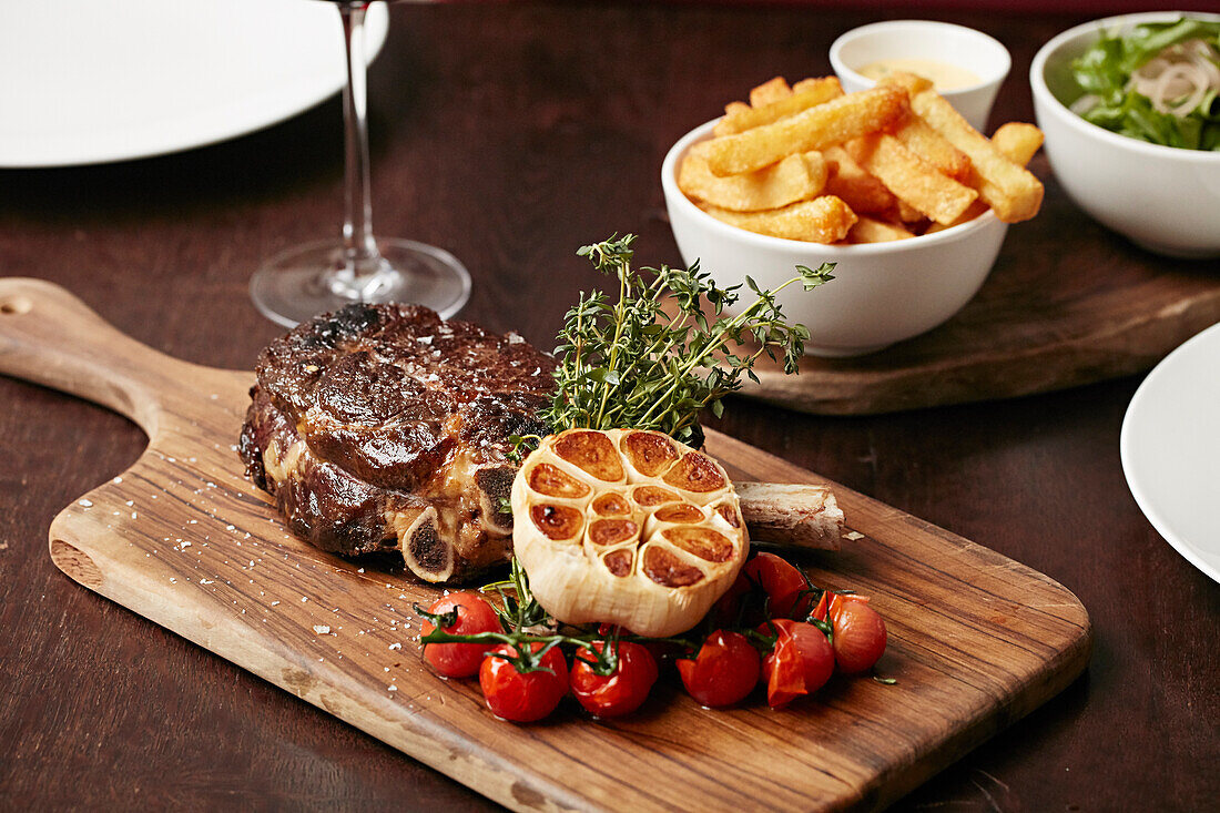 Tomahawk steak on a board with chips and red wine