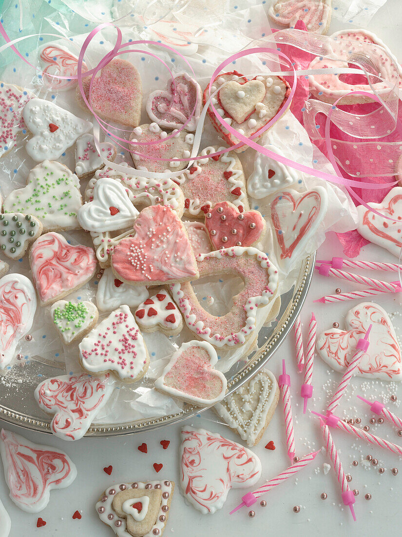 Heart-shaped cookies with sprinkles and royal icing in a bowl