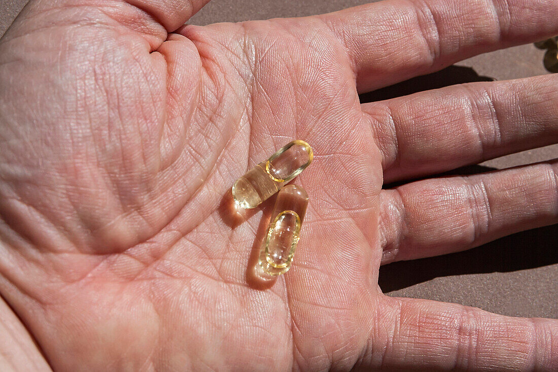 Hand holding garlic oil pills