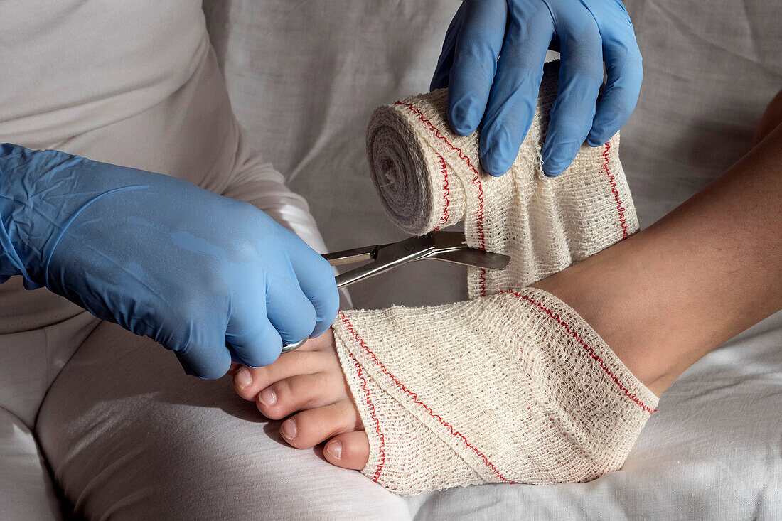Nurse tying bandage on patient's foot