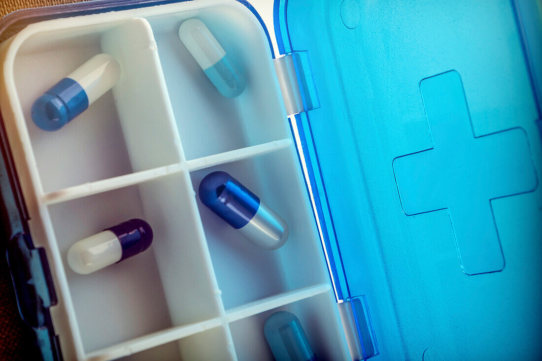 Blue and white capsules in a pill box