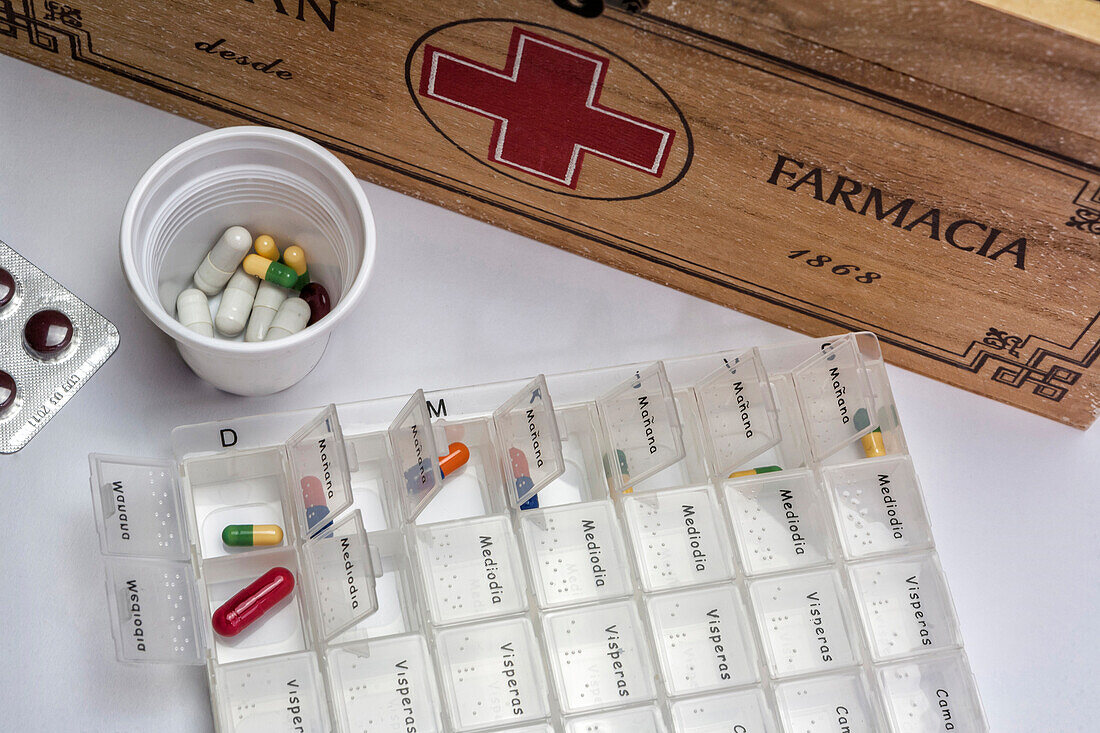 Pills with pill organizer next to old wooden kit