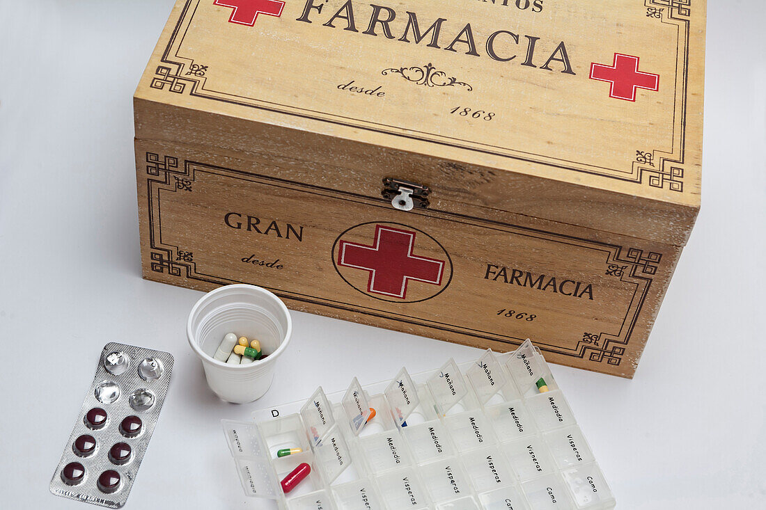 Pills in pill organizer next to an old wooden kit