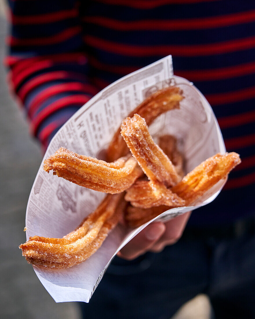 Hand holding paper bag with churros