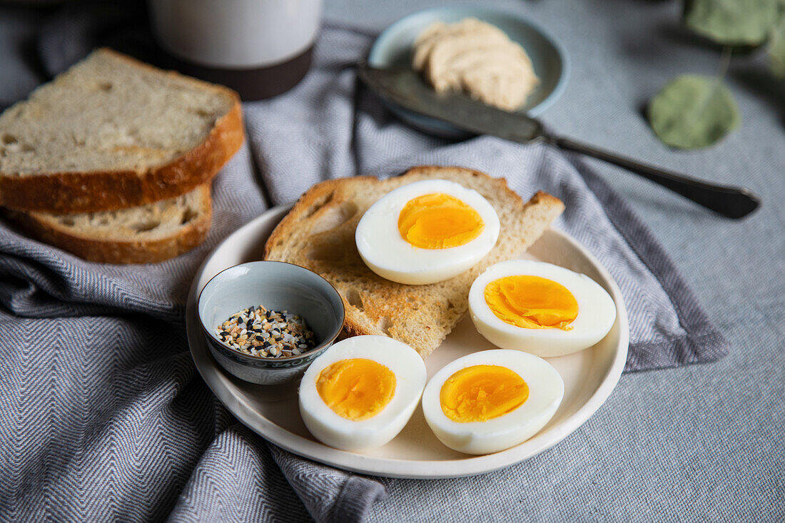Frühstück mit getoastetem Brot, gekochtem Ei und Hummus