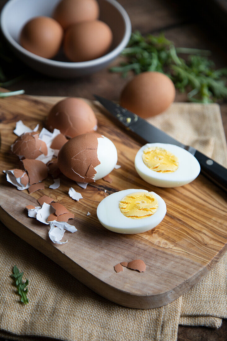 Hard boiled eggs, partially peeled, on a wooden board