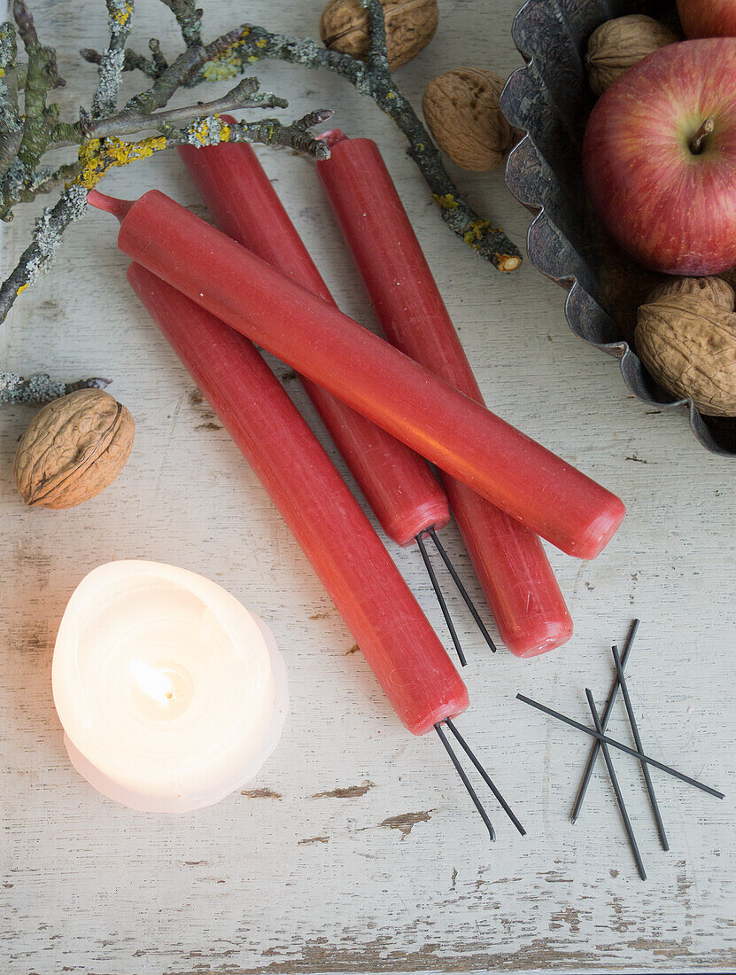 Brennende Kerze, Blumensteckdraht und rote Kerzen