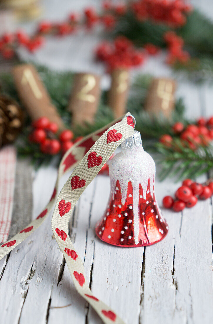 Glass ornament of a Christmas bell with heart ribbon