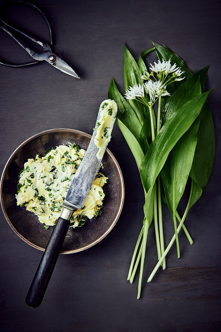 Wild garlic (ramps) butter next to fresh wild garlic with blossoms