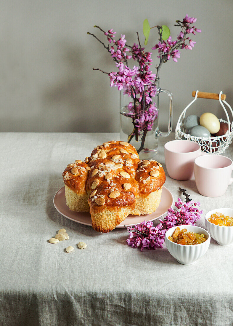 Colomba - traditional italian easter cake with almonds, easter table with pink flowers in a vase