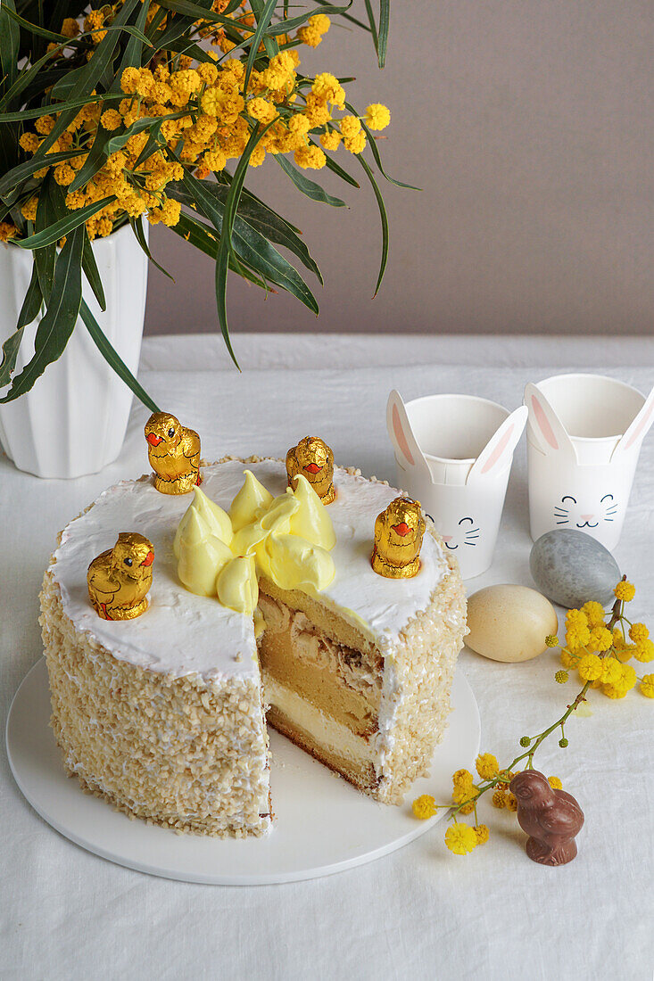 Ostertorte mit Schokoladenküken daneben ein Strauß Mimosen