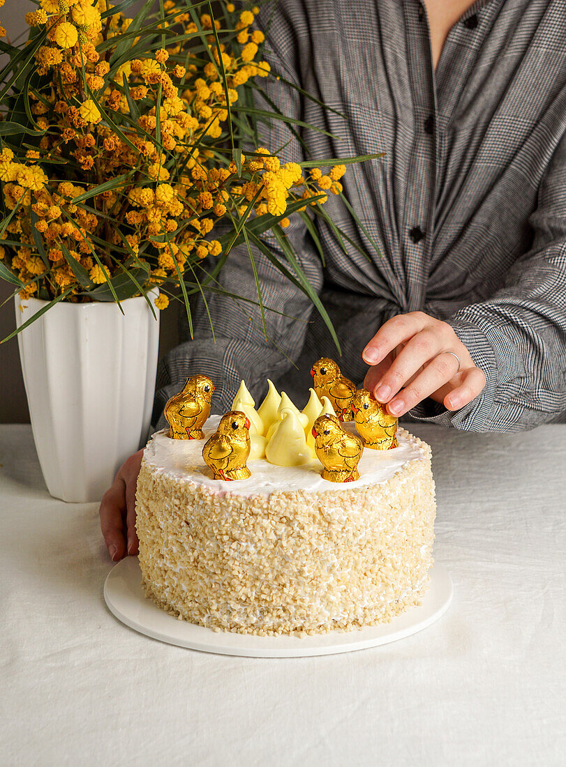 Ostertorte mit Schokoladenküken daneben ein Strauß Mimosen