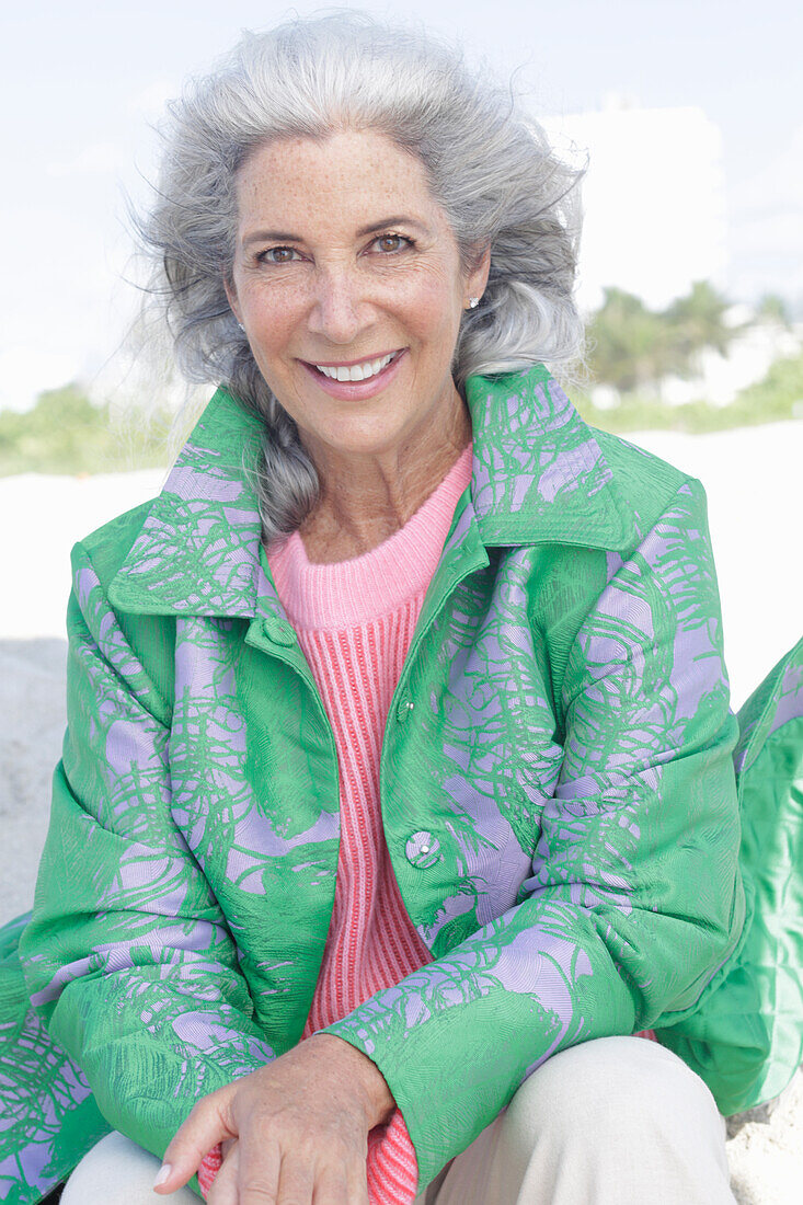 Grauhaarige Frau in grünem Mantel