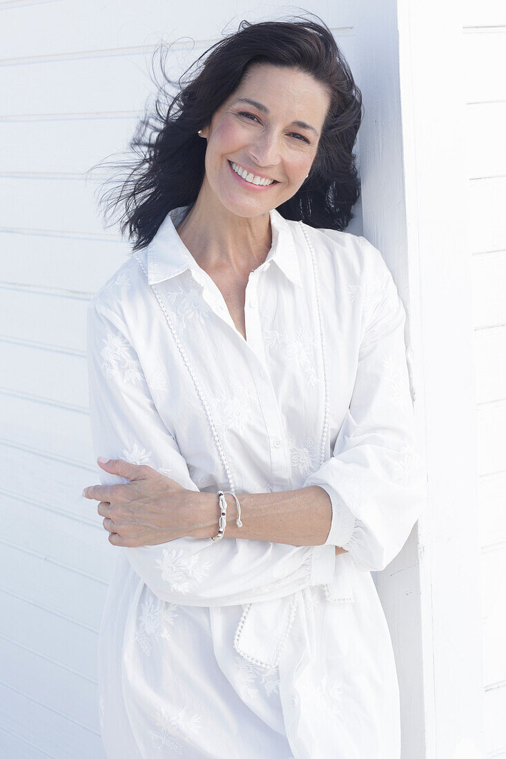 Mature dark-haired woman in white dress with embroidery