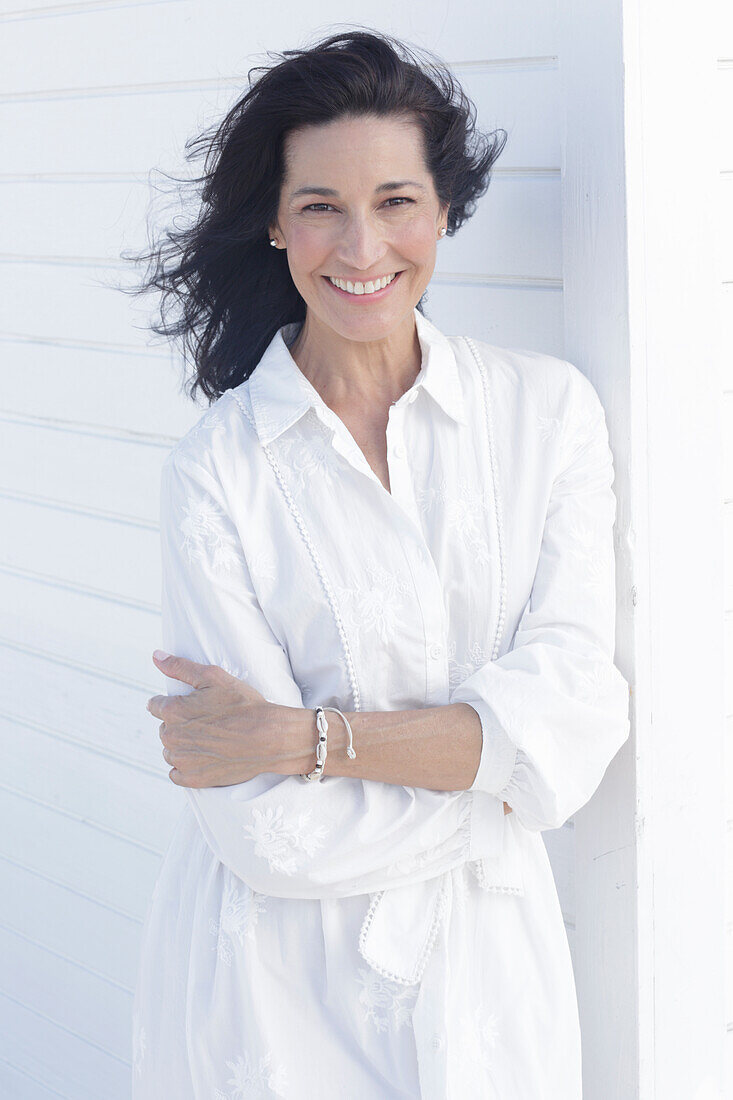 Mature dark-haired woman in white dress with embroidery