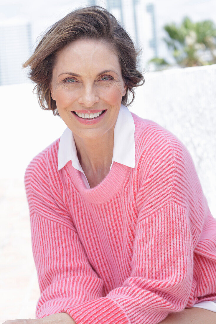 Woman in a pink sweater and white shirt on the beach