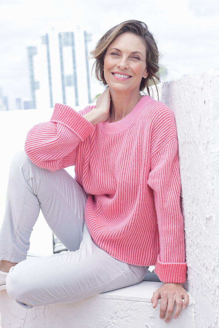 Frau in pinkfarbenem Pullover und weißer Hose