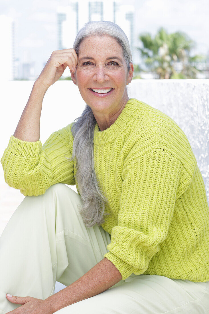 Gray-haired woman in a green-yellow knit sweater and light-colored trousers